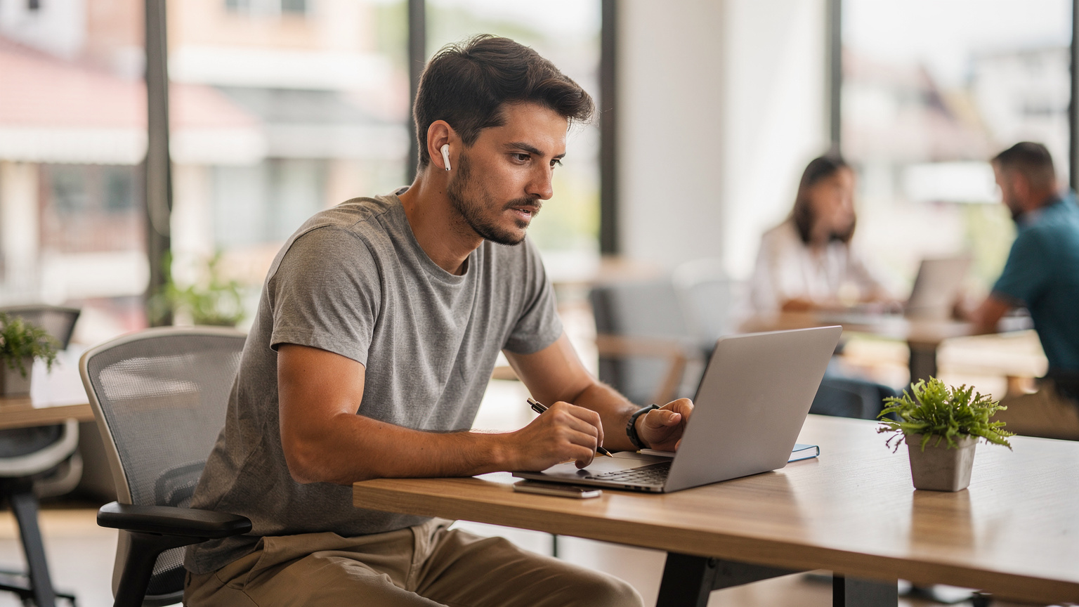 Un giovane nomade digitale italiano, concentrato sul suo laptop, partecipa a una videochiamata in uno spazio di coworking moderno e luminoso a Chiang Mai.